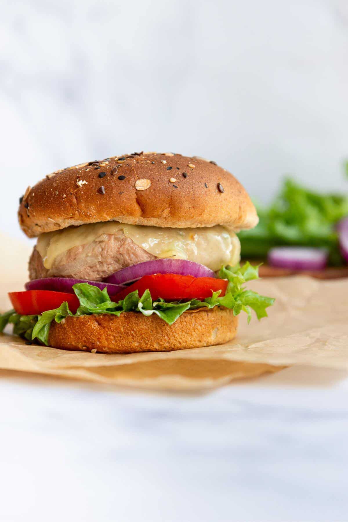 Assembling air fryer turkey burger on a toasted bun with lettuce, tomato, and onion.