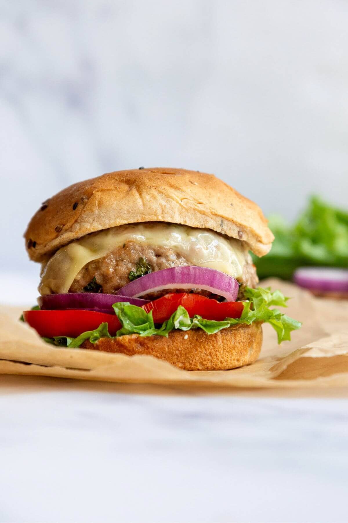 Juicy air fryer turkey burgers stacked on a bun with lettuce, onion, and tomato.