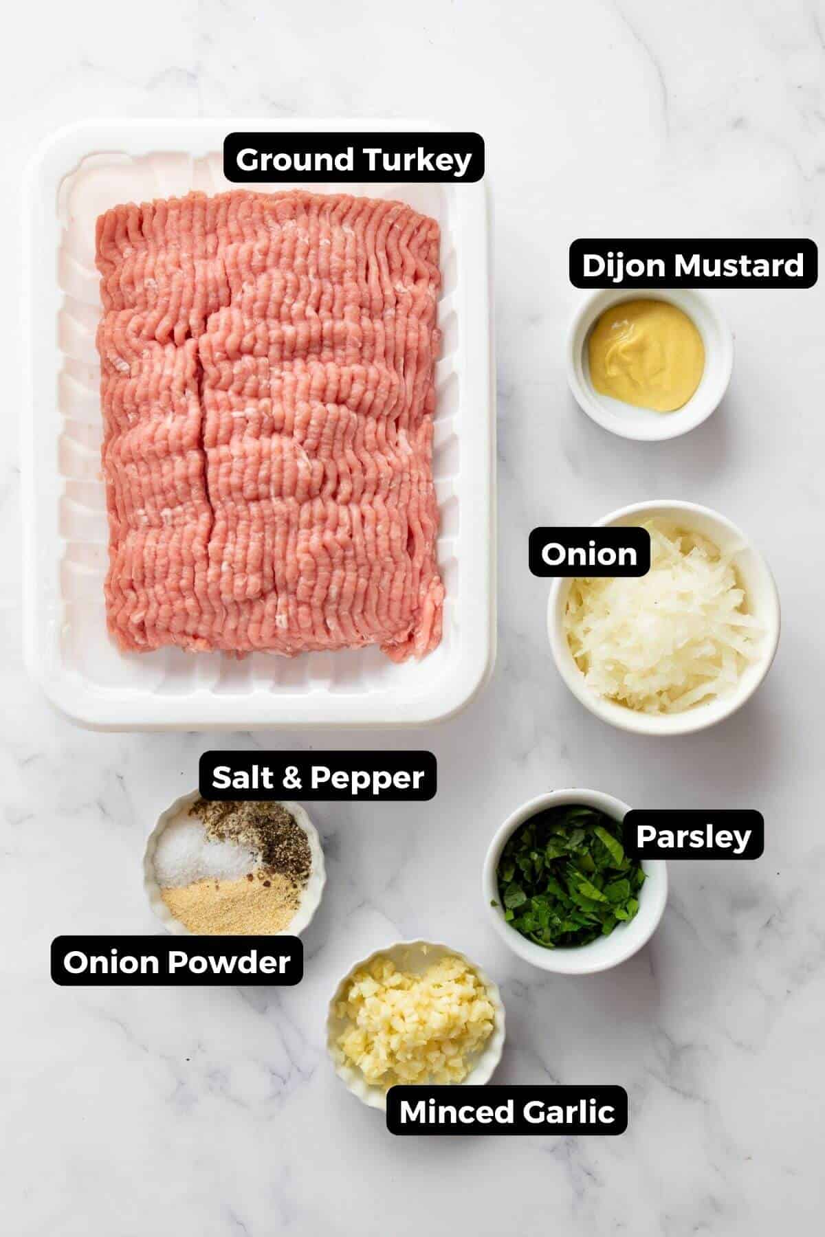 All turkey burger ingredients displayed in small labeled bowls, including ground turkey, minced garlic, shredded onion, chopped parsley, Dijon mustard, onion powder, Italian seasoning, salt, and black pepper.
