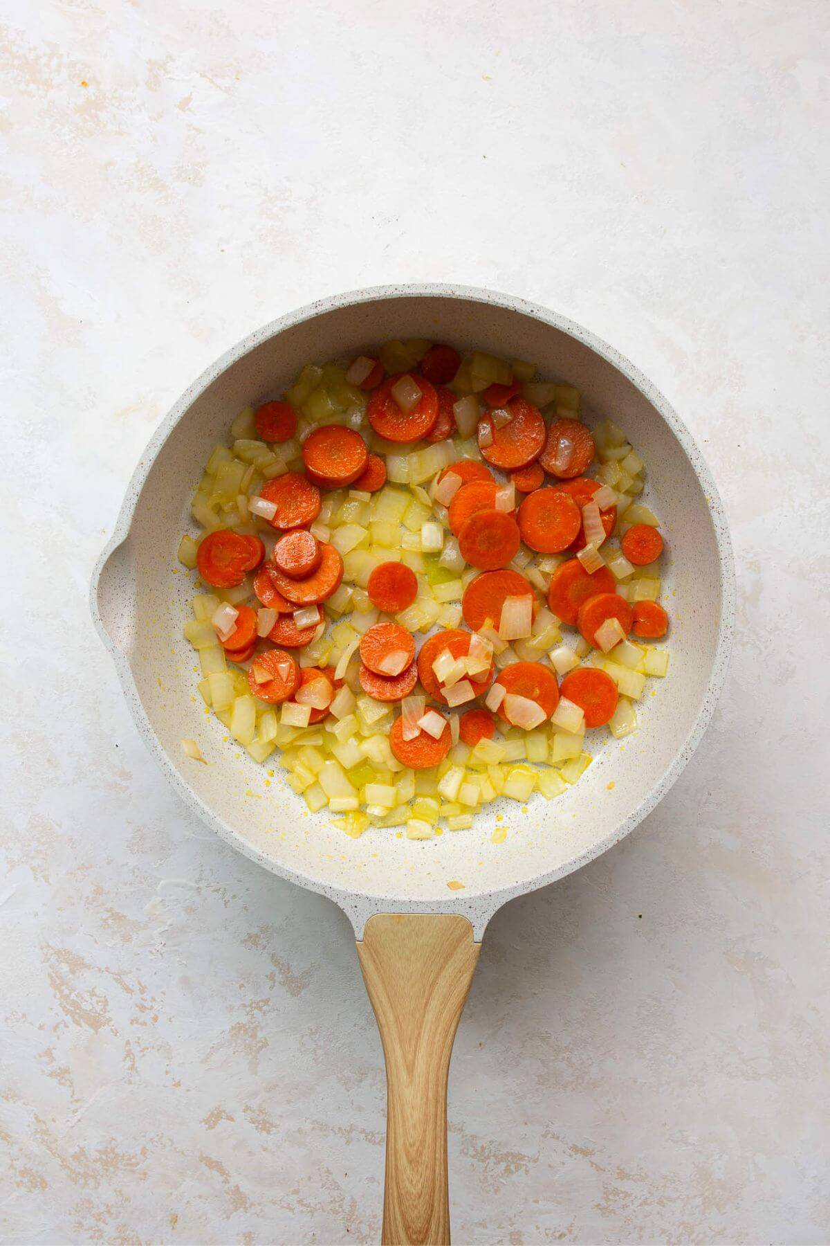 Sautéing diced onions, carrots, and garlic in olive oil in a large skillet until softened.