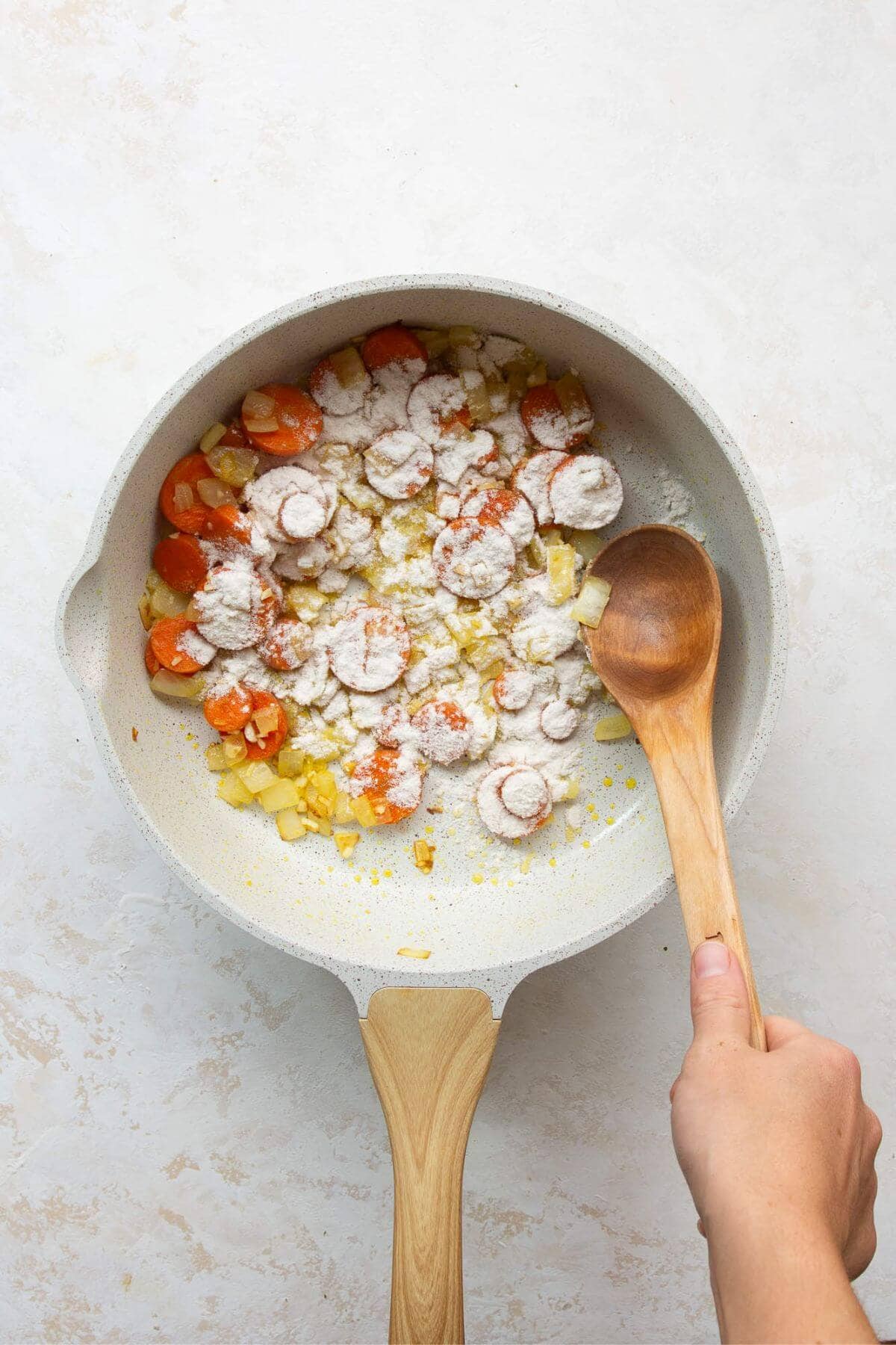 Sprinkling gluten-free flour over the sautéed vegetables to thicken the filling.