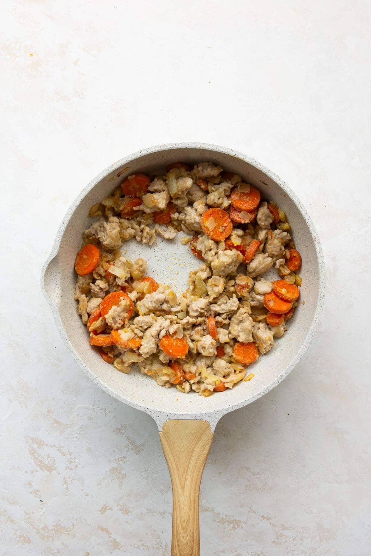 Cooking lean ground chicken with onions and carrots in a skillet until browned and crumbly.