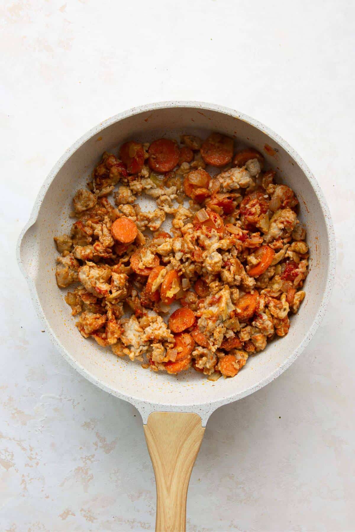 Stirring tomato paste, Worcestershire sauce, and spices into the cooked meat mixture.