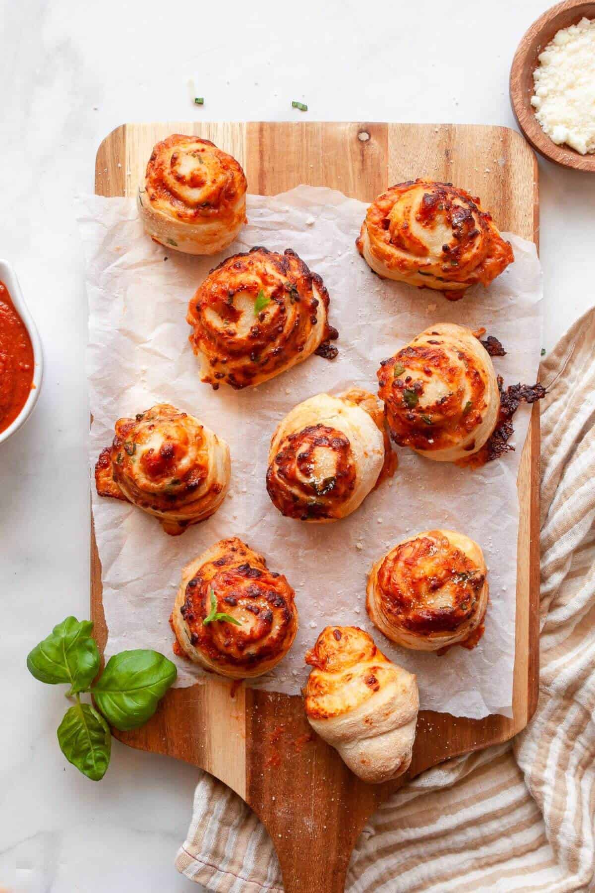 Golden, cheesy homemade air fryer pizza rolls on a cutting board after air frying.