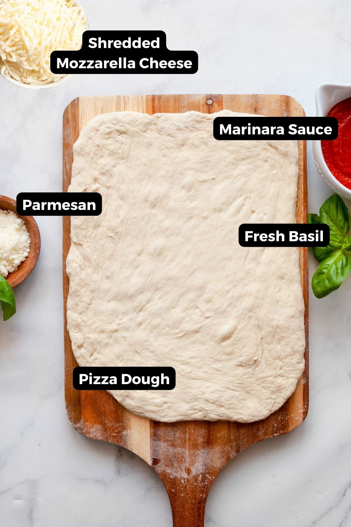 Ingredients for homemade air fryer pizza rolls including pizza dough, marinara sauce, shredded mozzarella, parmesan, and fresh basil on a countertop.