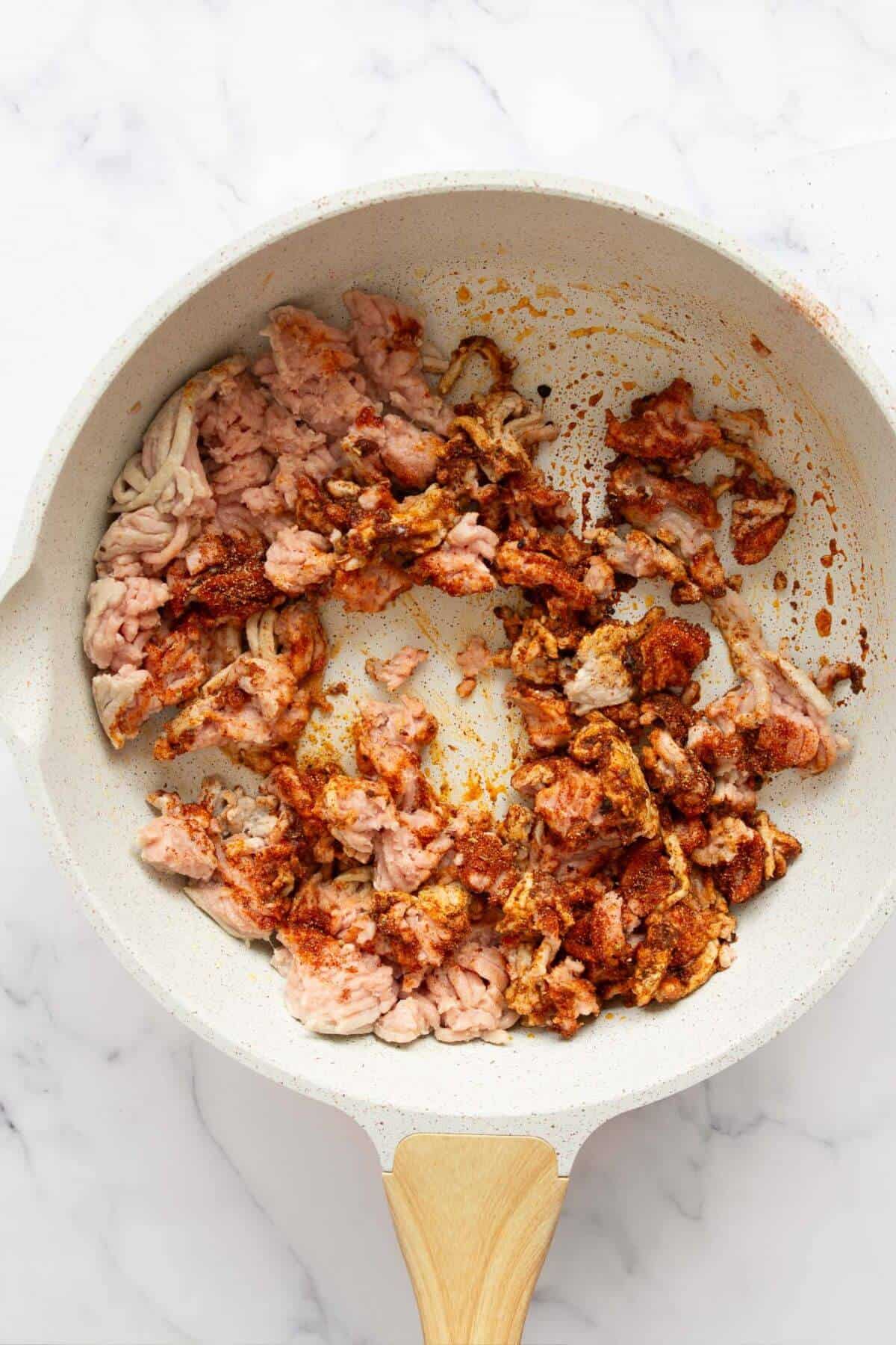 Cooking raw ground turkey with the homemade seasoning in a pan.