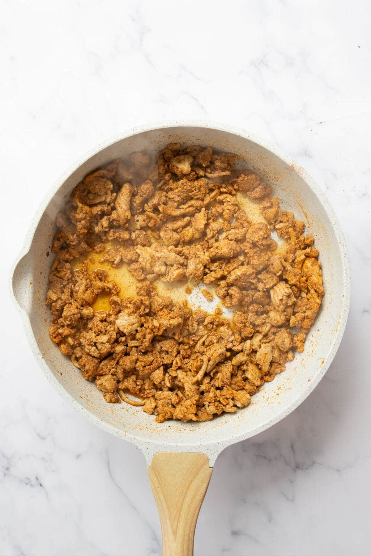 Cooked juicy and seasoned ground turkey in a pan.