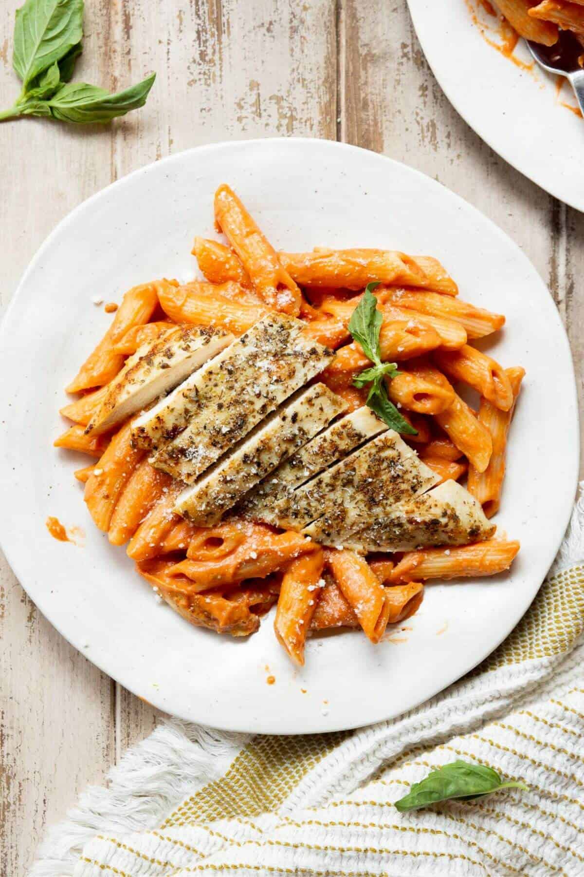 Plated penne alla vodka with chicken topped with fresh basil and parmesan, made with Greek yogurt instead of heavy cream.