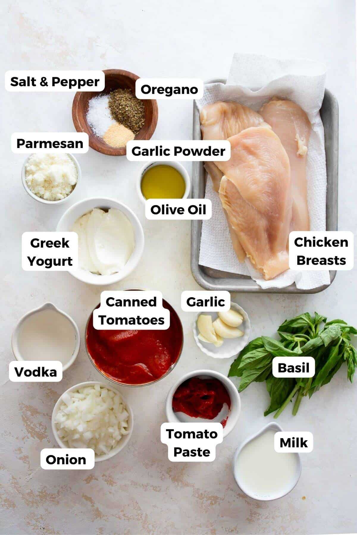 Ingredients for healthy penne alla vodka with chicken, including Greek yogurt, crushed tomatoes, vodka, parmesan, and fresh basil.