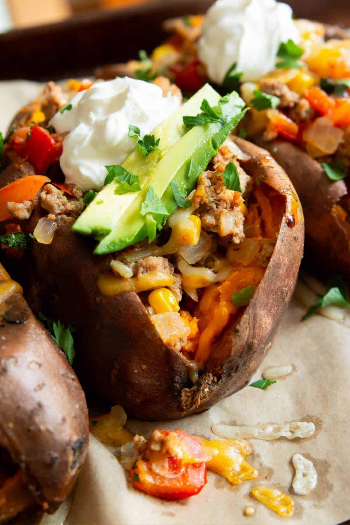 Turkey taco stuffed sweet potatoes with ground turkey, cheese, avocado, and sour cream.