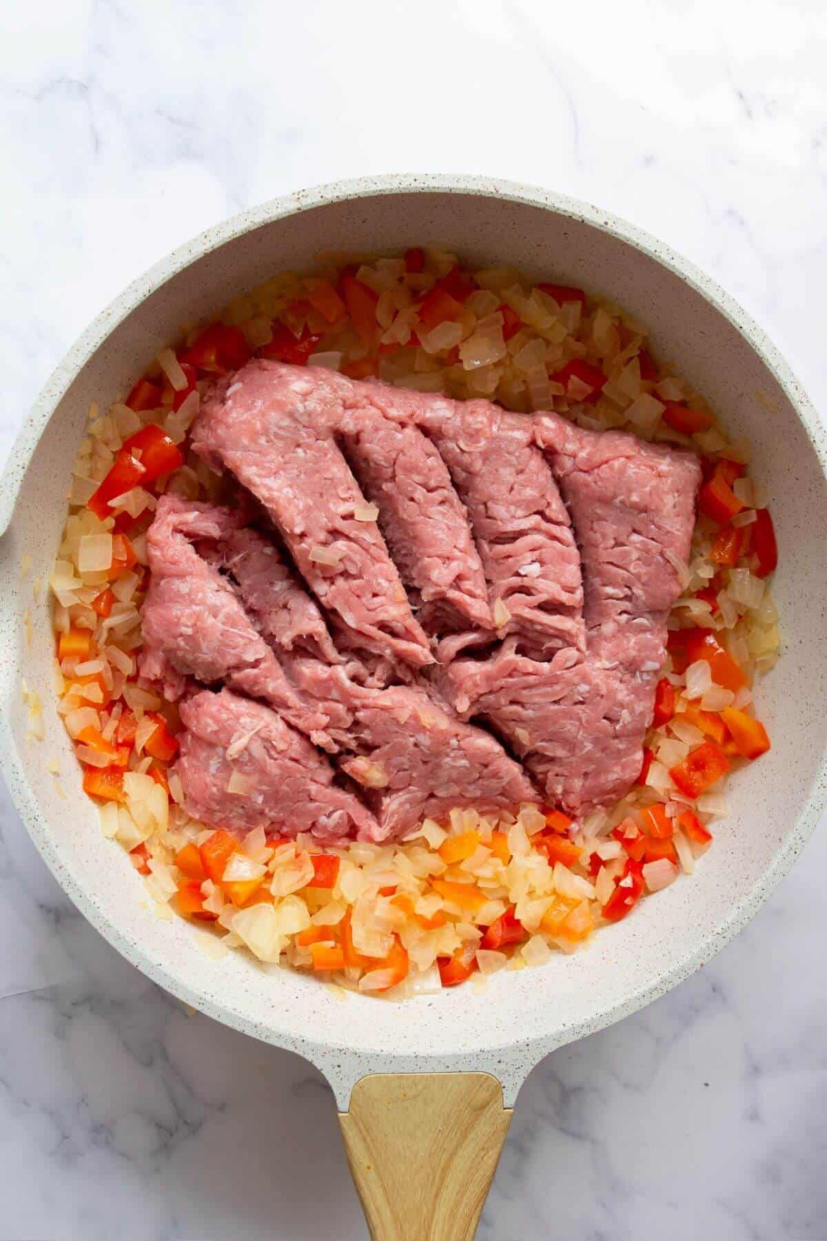 Raw ground turkey cooking with vegetables for taco stuffed sweet potatoes.