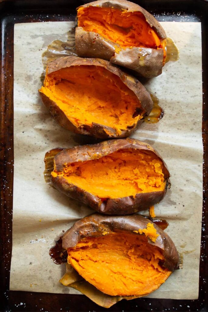 four sweet potato boats on a baking sheet