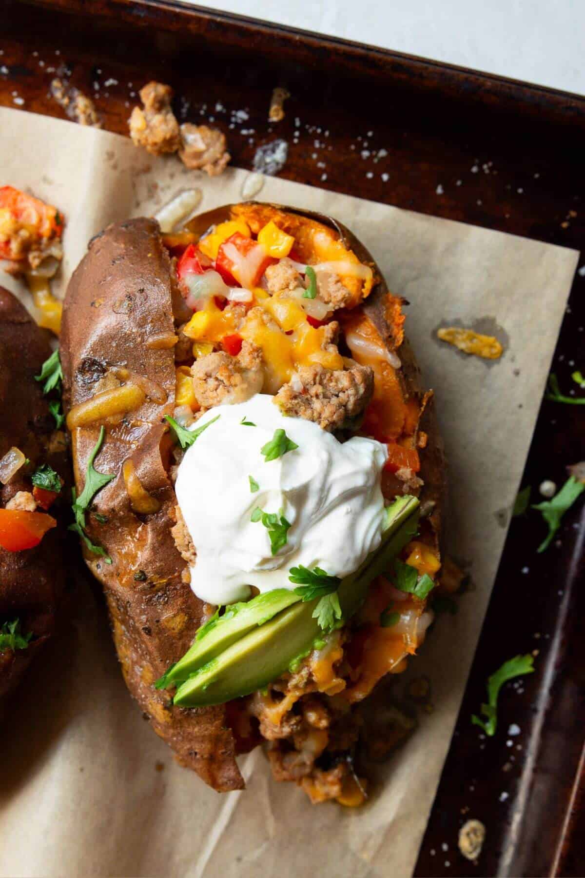 Healthy ground turkey taco stuffed sweet potatoes with greek yogurt and avocado on top.