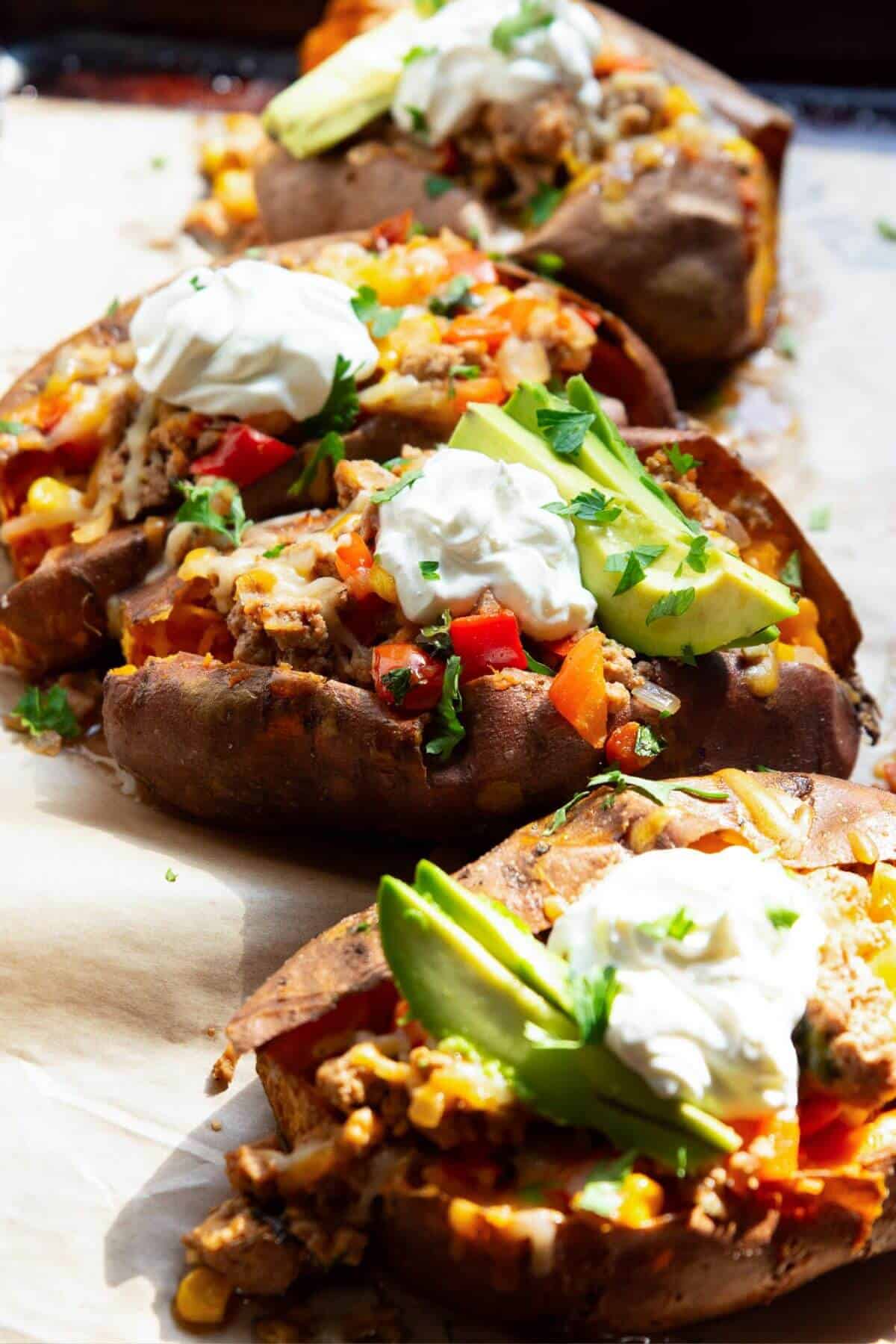 Topping taco stuffed sweet potatoes with avocado, yogurt, and cilantro.