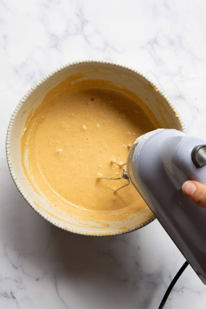whisking healthy, high-protein pumpkin cheesecake batter in a mixing bowl