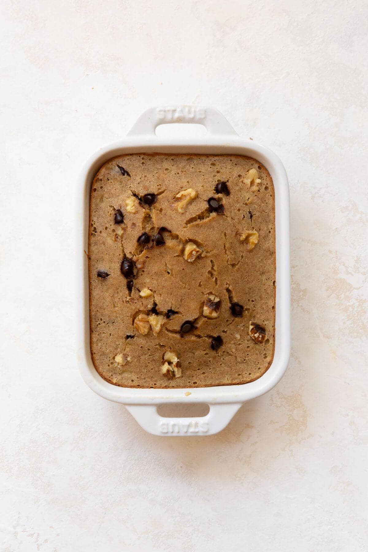 Baked single serve banana bread in a white ramekin, fresh from the oven.