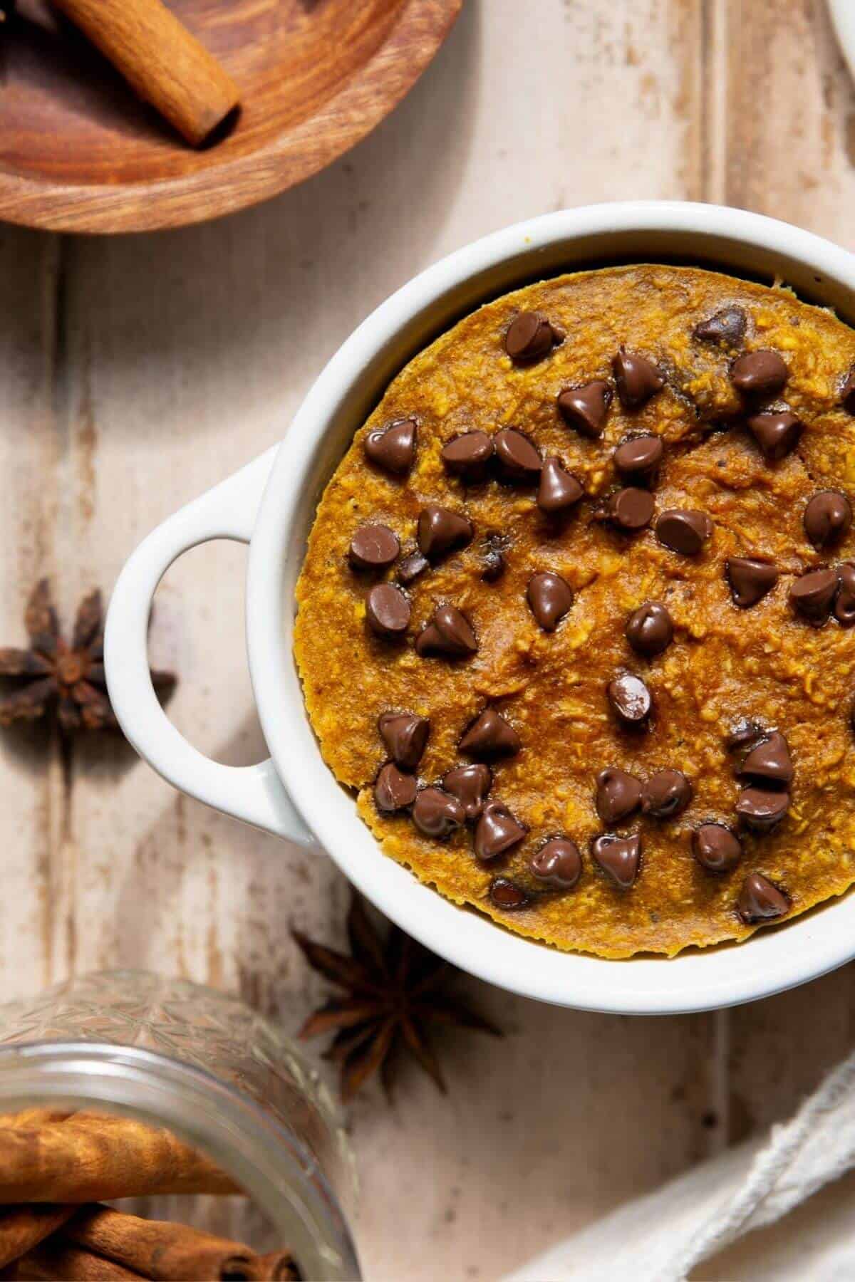 Close up of blended pumpkin baked oats with a golden top and melted chocolate chips.