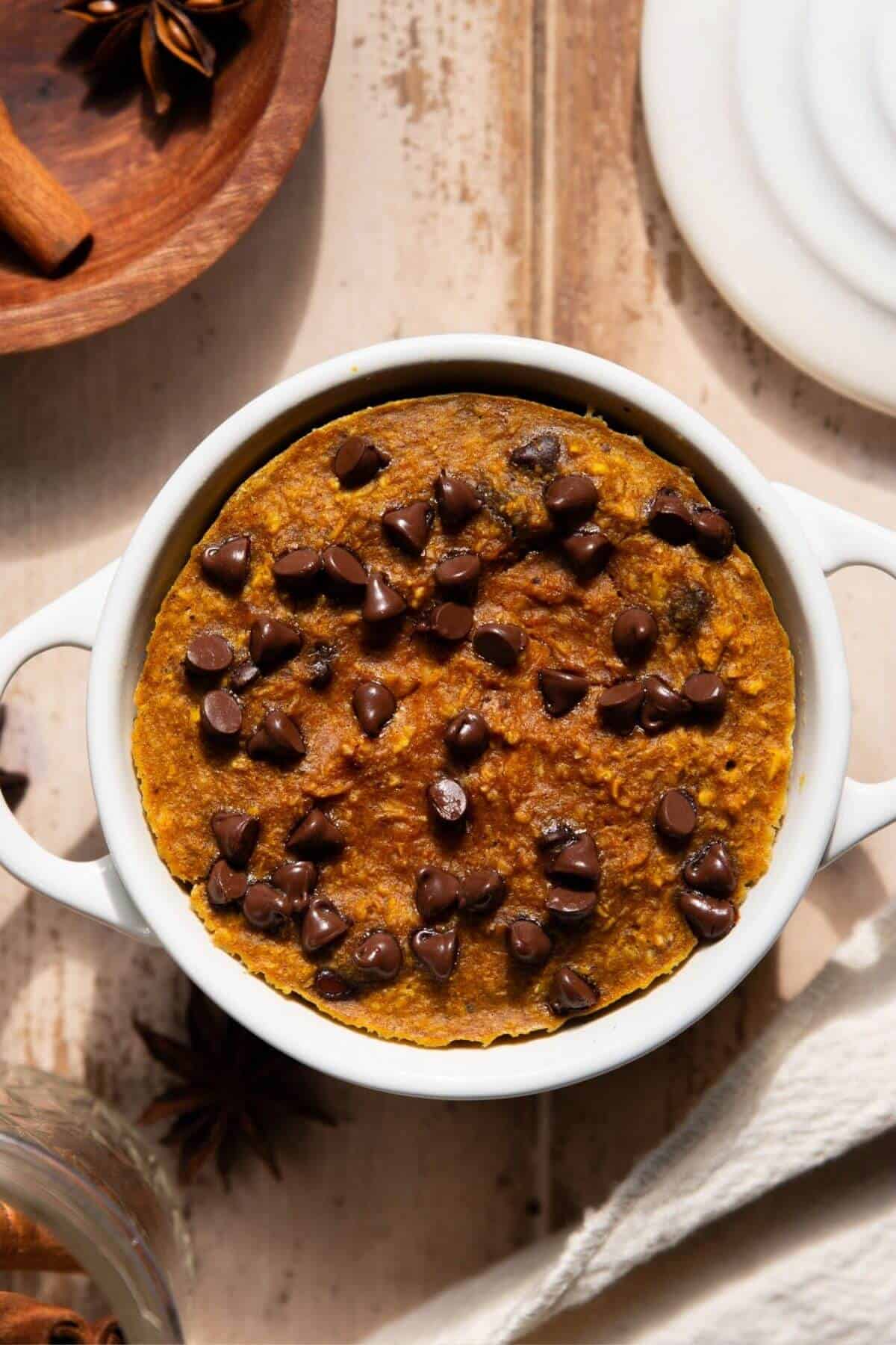 Single serve blended pumpkin baked oats in a white ramekin with chocolate chips.