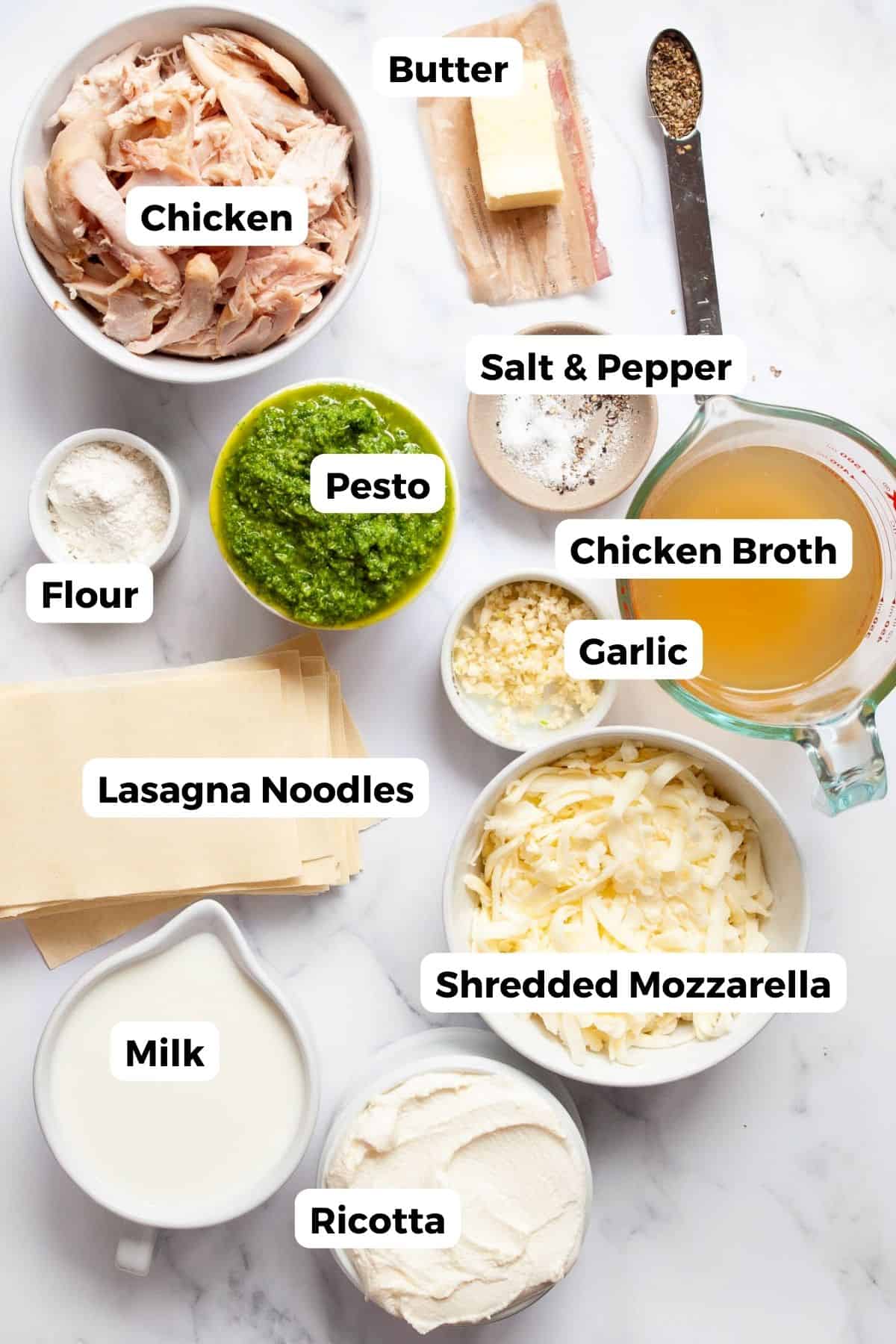 All ingredients for chicken and broccoli lasagna arranged in small bowls with labels, including shredded chicken, ricotta, milk, mozzarella, broccoli, basil, garlic, olive oil, and lasagna noodles.