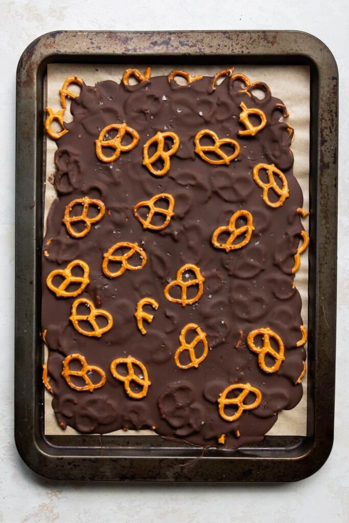 salted dark chocolate pretzel bark on a baking sheet after setting