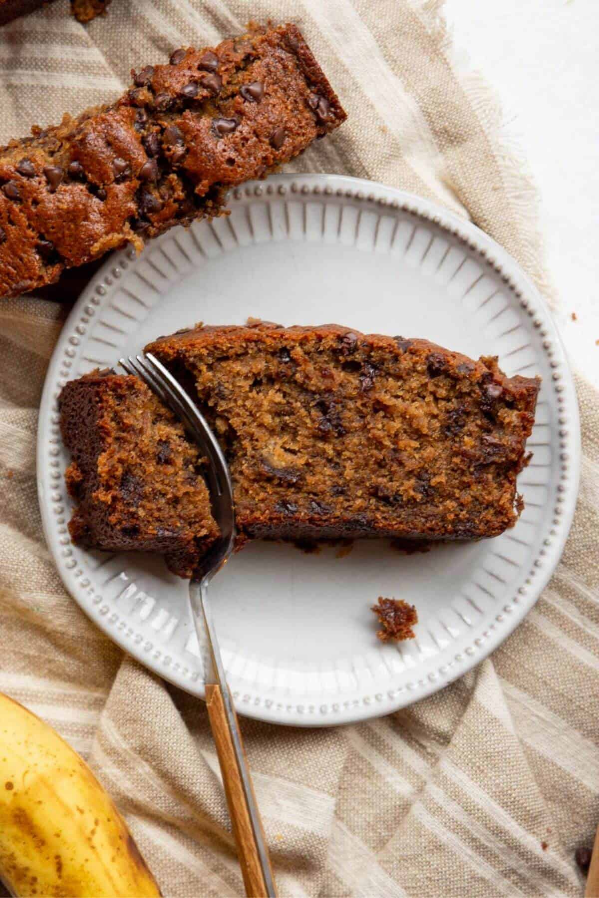 Slice of gluten-free oat flour banana bread on a plate to show moist, soft crumb.