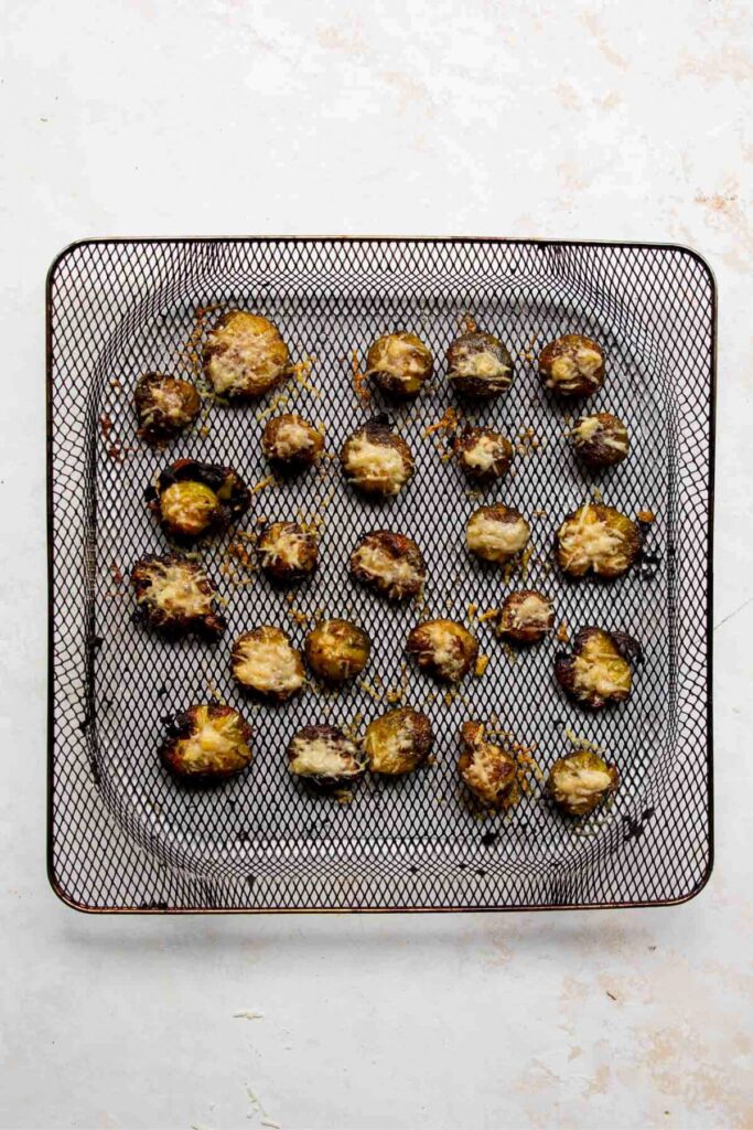 crispy and cheesy smashed Brussels sprouts in air fryer basket after cooking