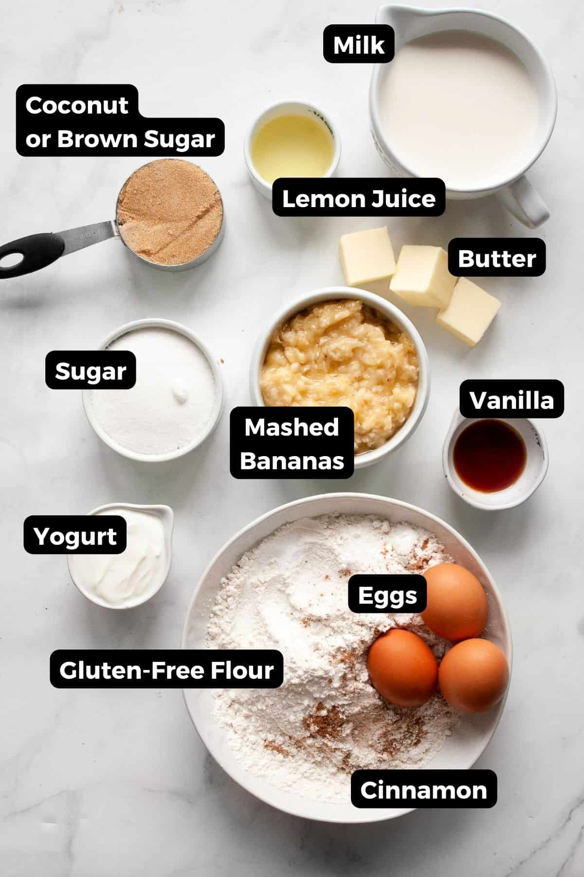 Ingredients for gluten-free banana cake including mashed bananas, gluten-free flour, eggs, yogurt, butter, cinnamon, sugar, lemon juice, and vanilla.