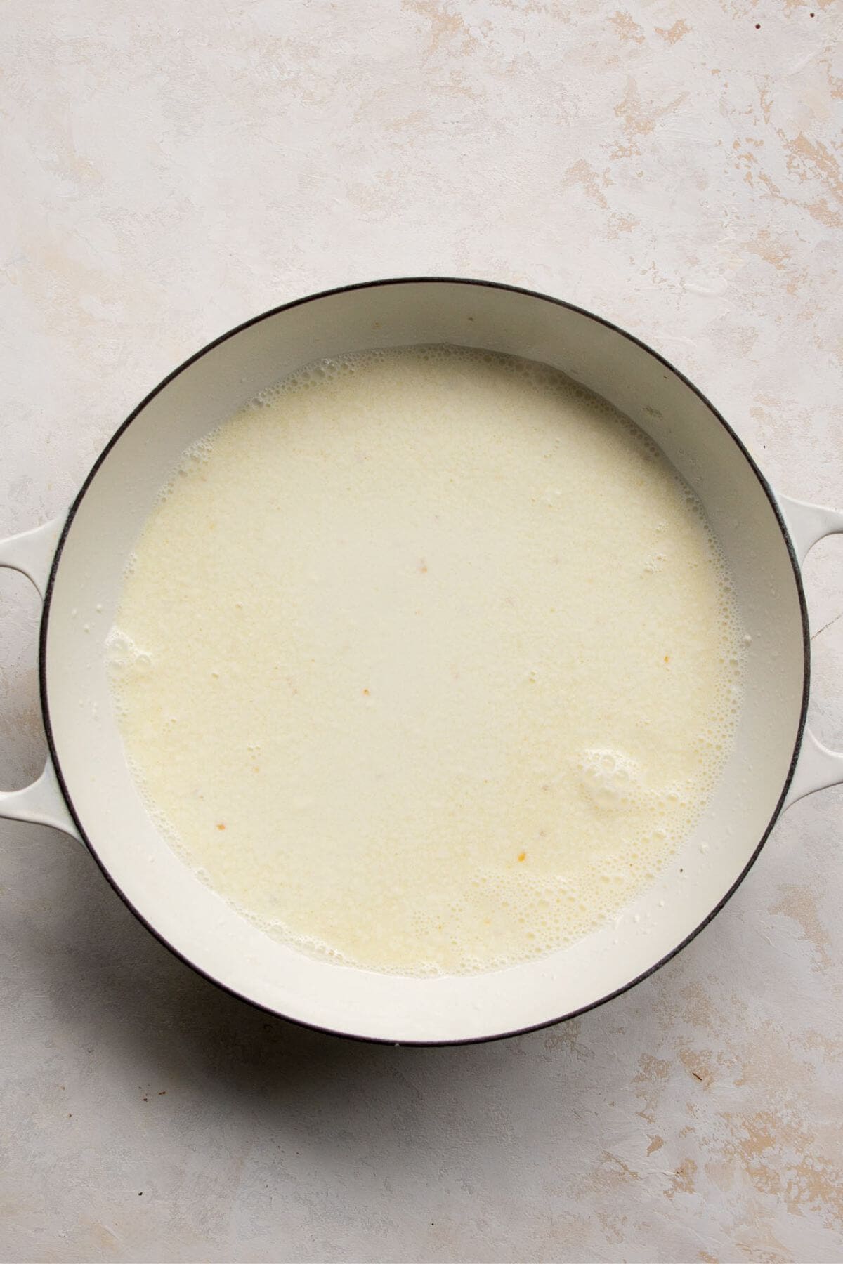 Pouring skim milk into garlic to form creamy sauce.
