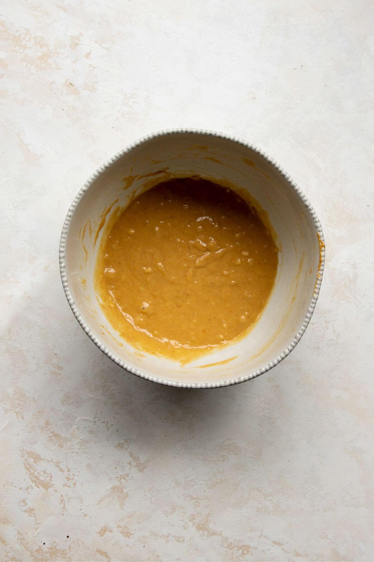 Mixing mashed bananas, peanut butter, and an egg in a mixing bowl to start banana oat breakfast cookie batter.