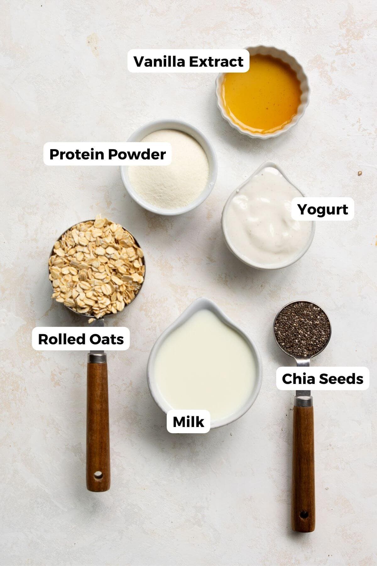All ingredients in protein overnight oats including: rolled oats, protein powder, greek yogurt, chia seeds, milk, and vanilla extract.