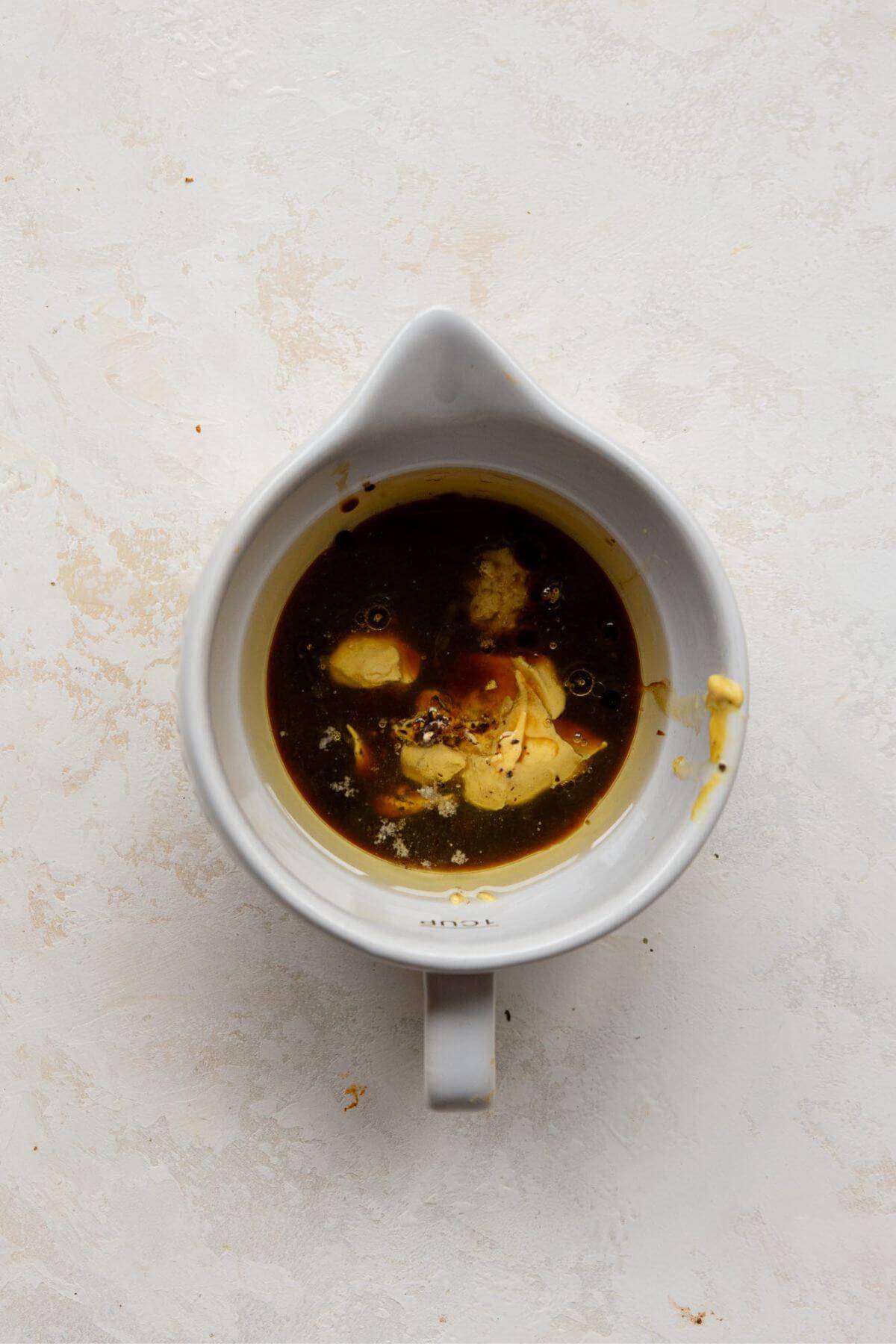 Balsamic vinaigrette ingredients in a mixing cup.