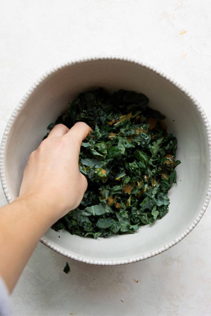 messaging kale in a bowl with balsamic vinaigrette