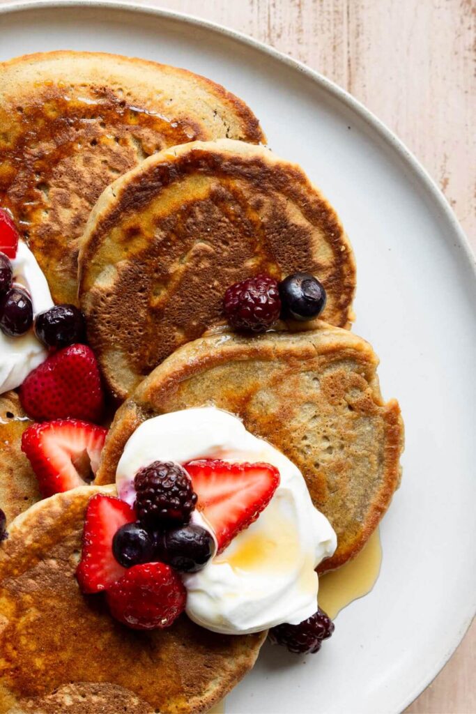 oat flour pancakes with crispy, buttery edges on a plate with syrup