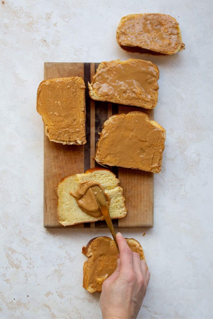 spreading peanut butter on top of slices of brioche