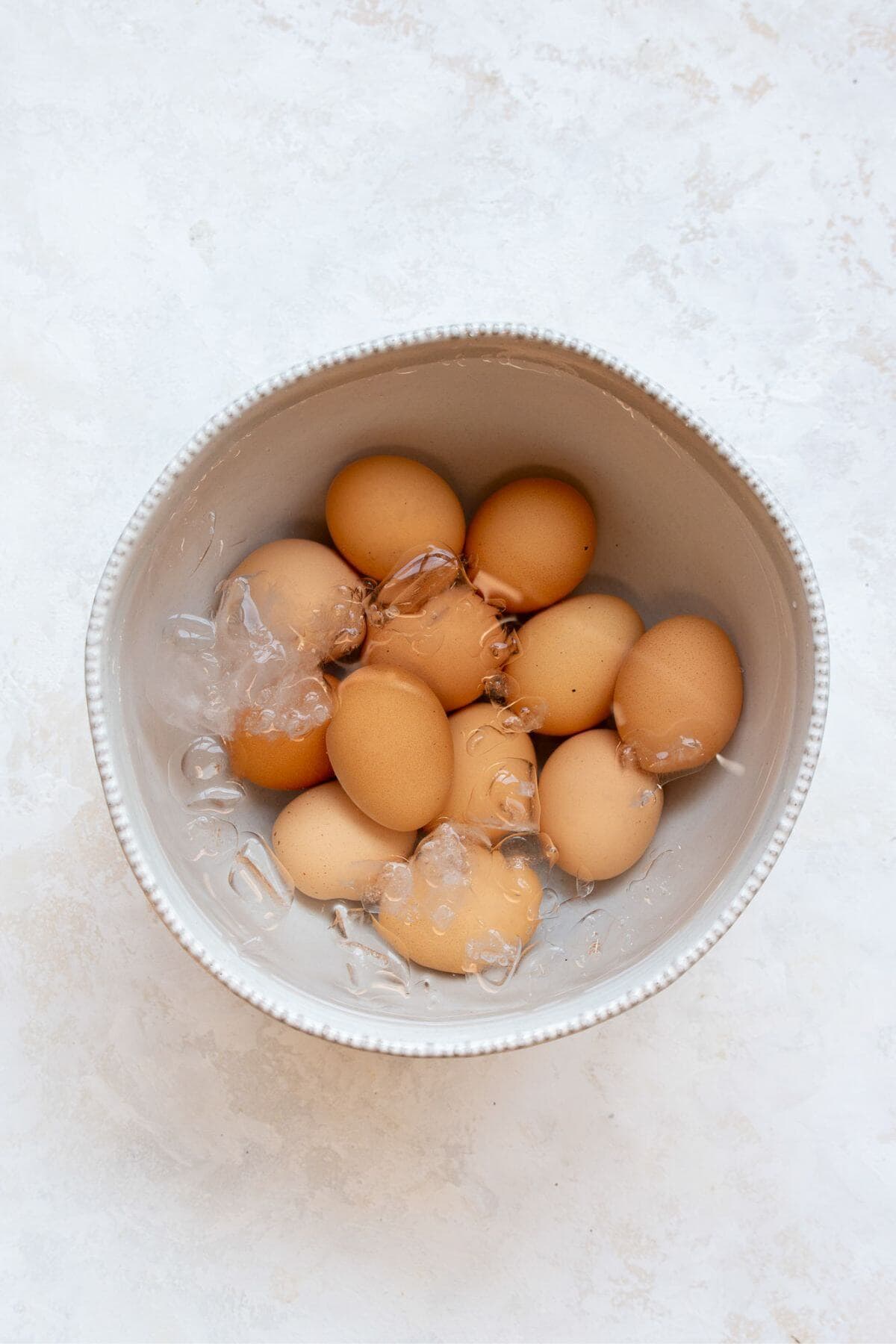 Cooked air fried soft boiled eggs cooling in an ice water bath.
