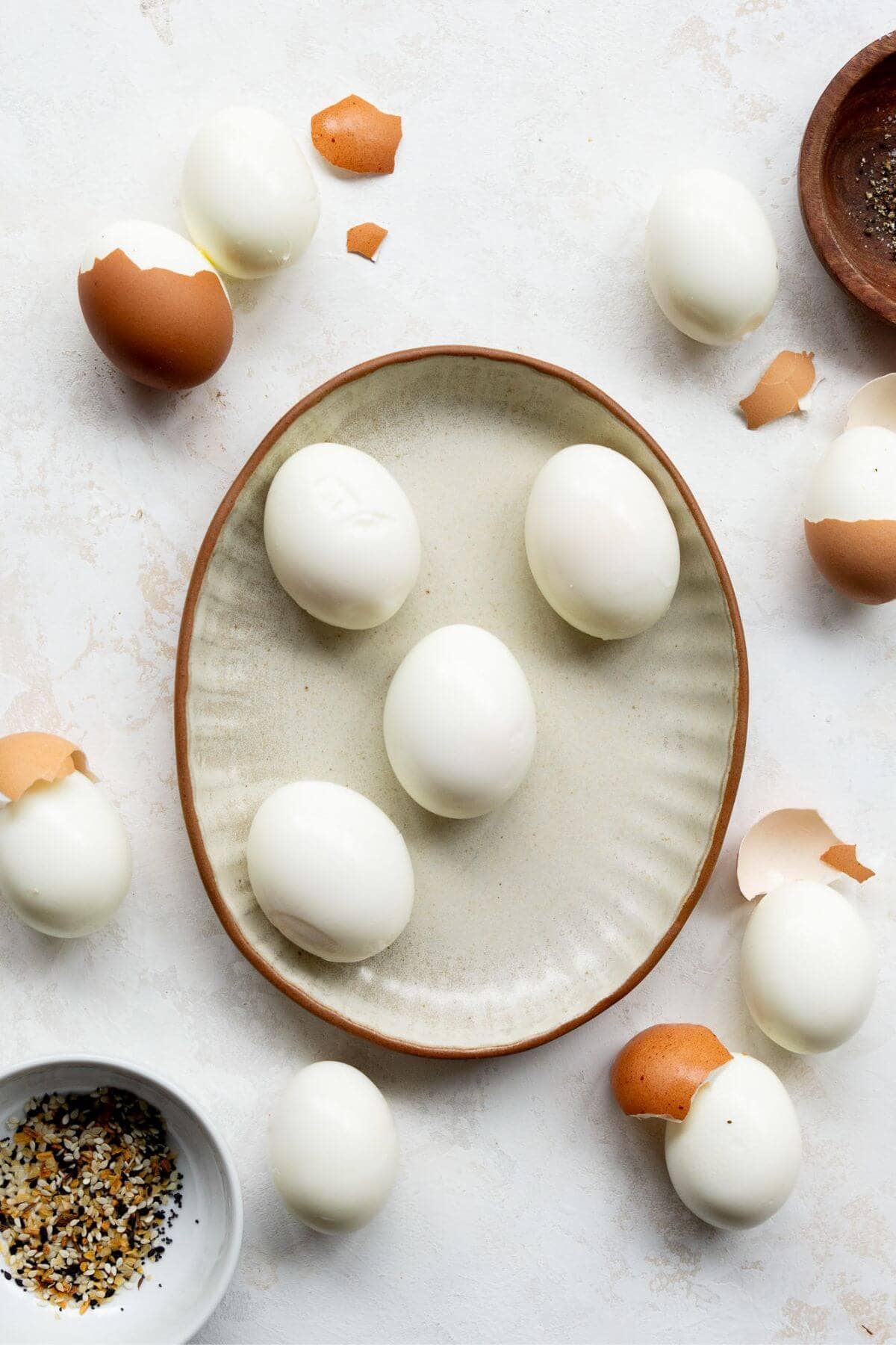 Peeled soft boiled eggs on a plate next to cracked shells.