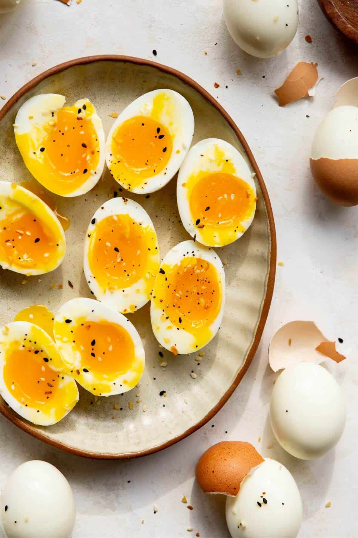 Air fryer soft boiled eggs sliced open with everything bagel seasoning on a plate.