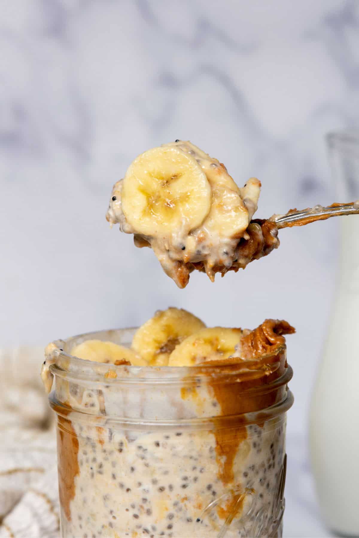 A spoon scooping overnight oats topped with fresh banana slices.