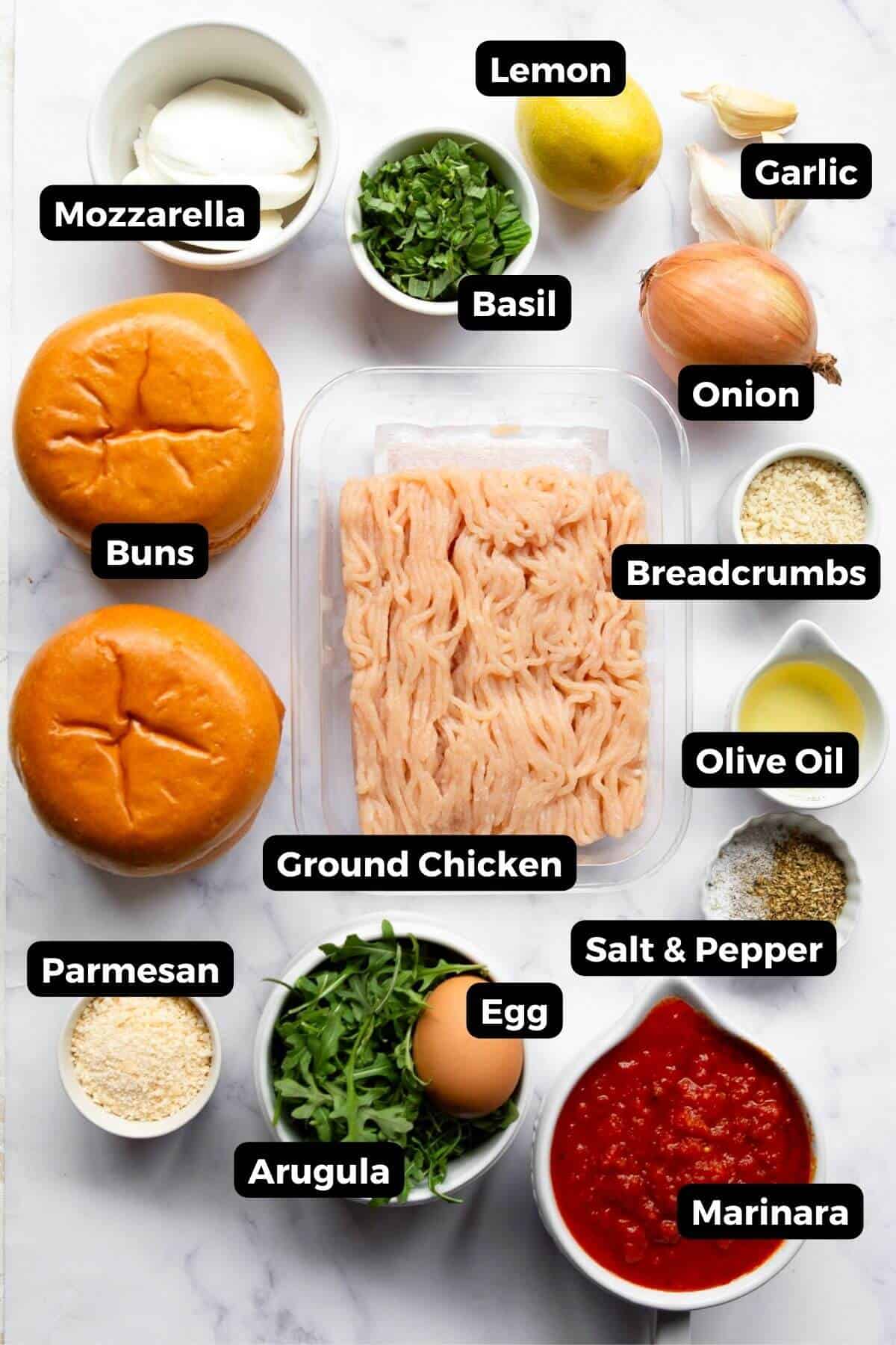 Ingredients for chicken parm burgers including ground chicken, mozzarella, parmesan, panko, egg, onion, garlic, basil, marinara, arugula, lemon, and buns.