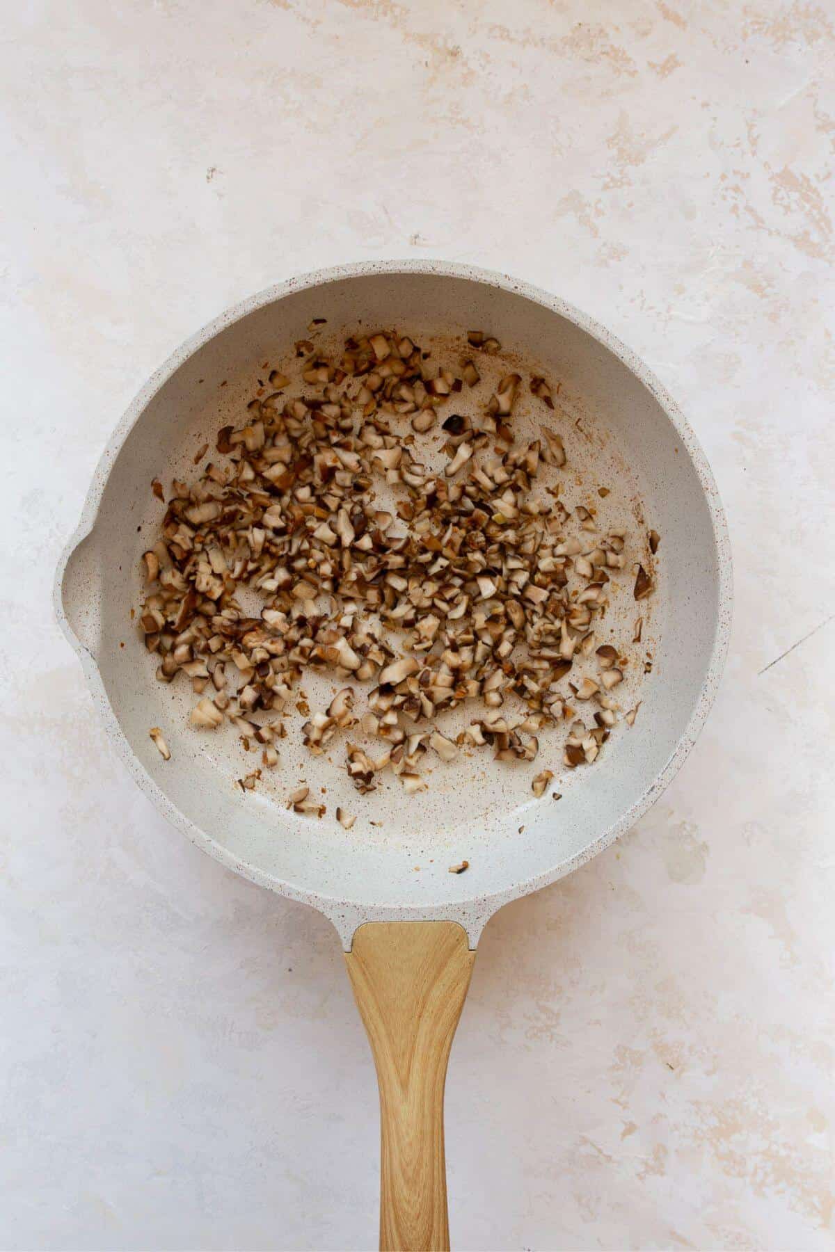 Chopped mushrooms browning in a skillet for spring roll filling.