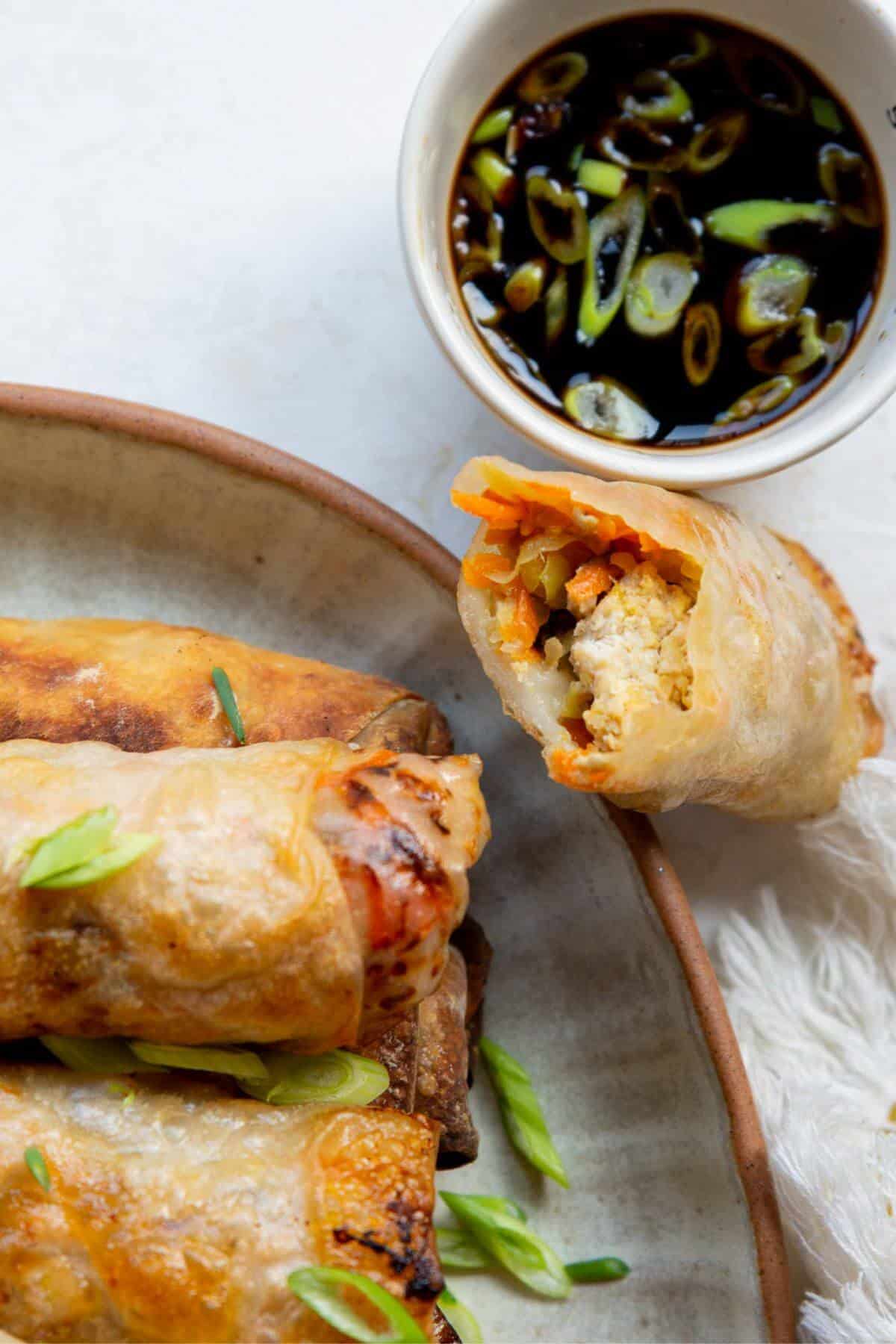 Golden air fryer spring rolls cut open to show the ground chicken and vegetable filling.
