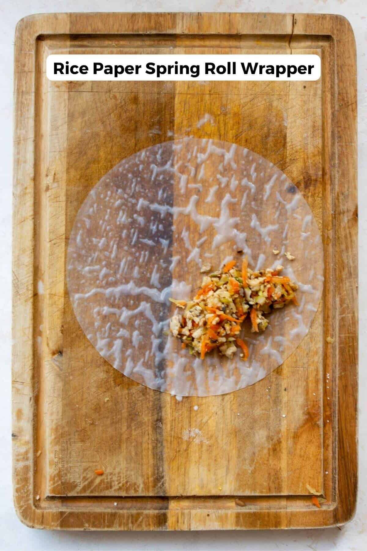 Spring roll filling on a softened round rice paper wrapper on a cutting board.