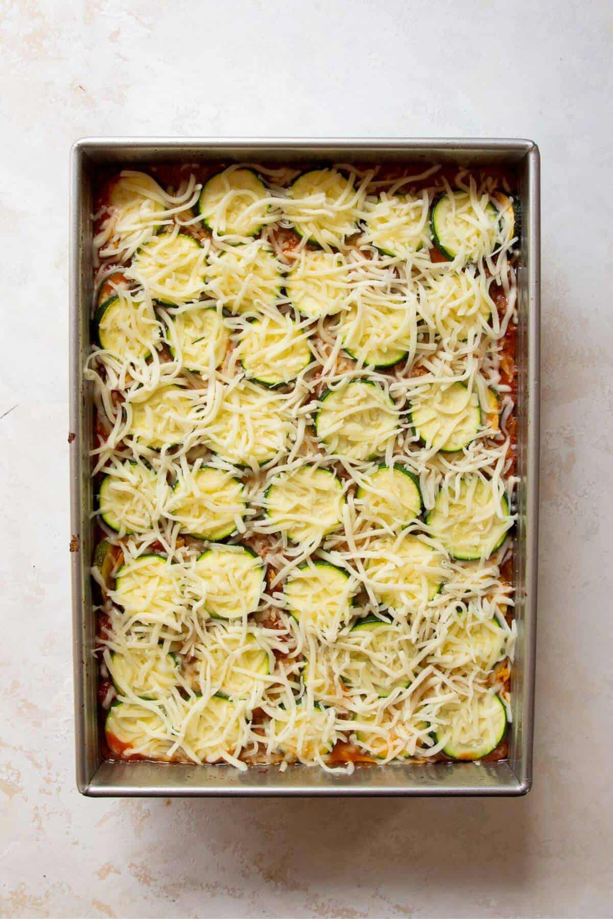 Adding a top layer of zucchini rounds and sprinkling mozzarella cheese over the ground beef casserole before baking.