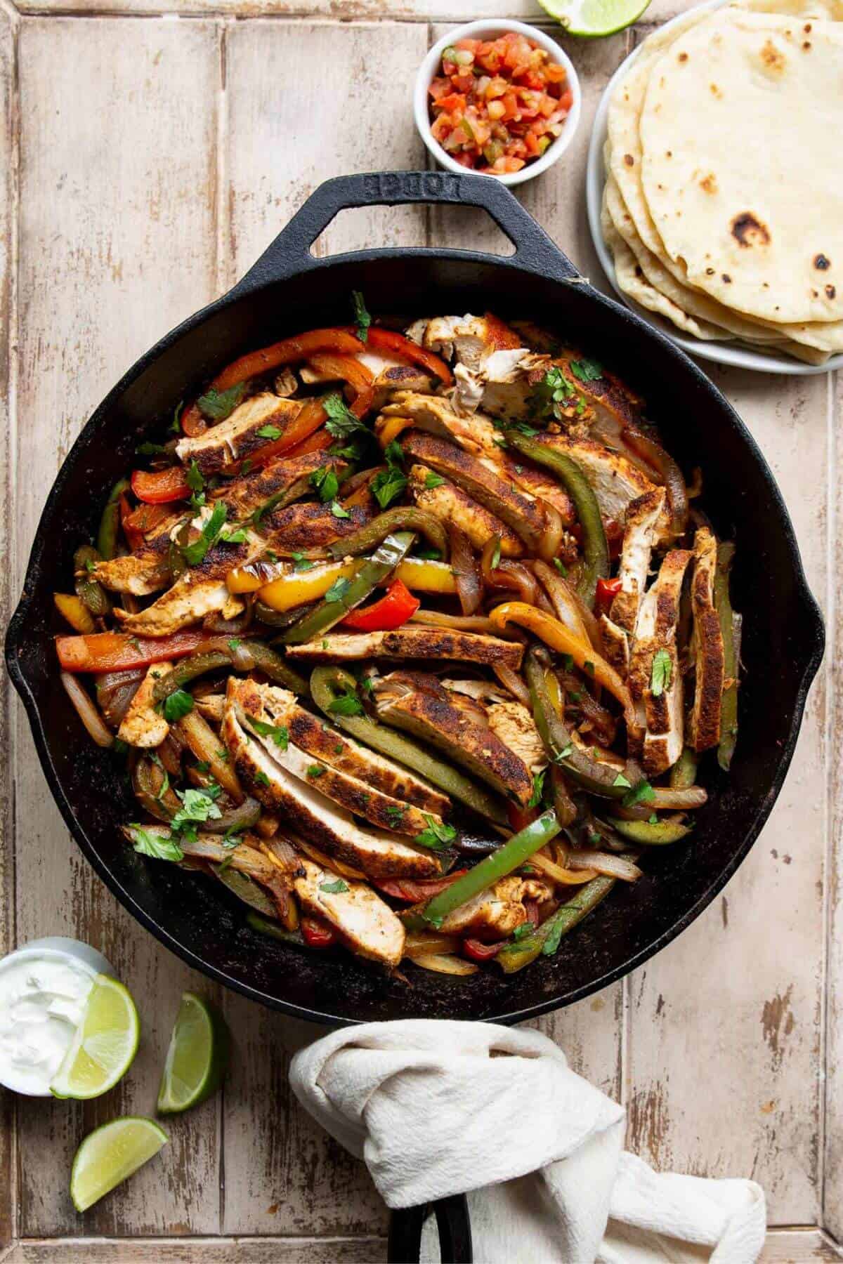 Cast iron skillet of chicken fajita taco filling with peppers and onions.