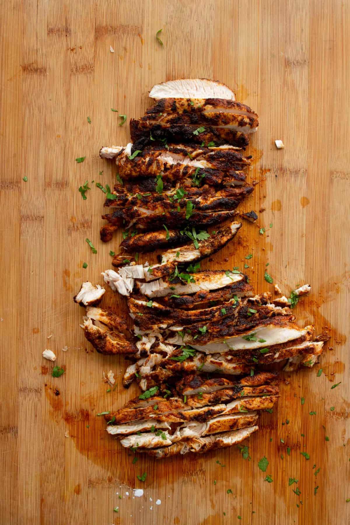 Thinly sliced seared fajita chicken breast on a cutting board.