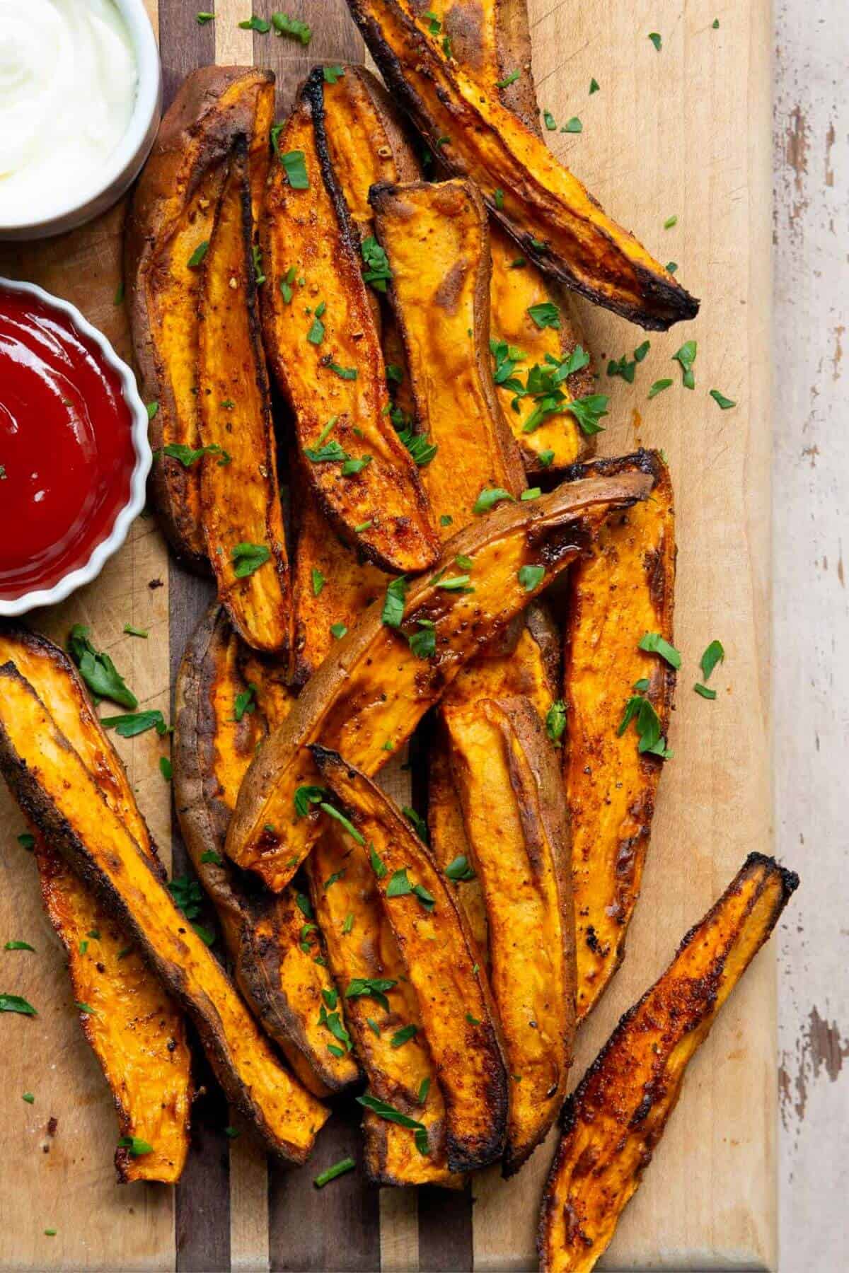Tender and crispy air fryer sweet potato wedges on a cutting board with parsley.