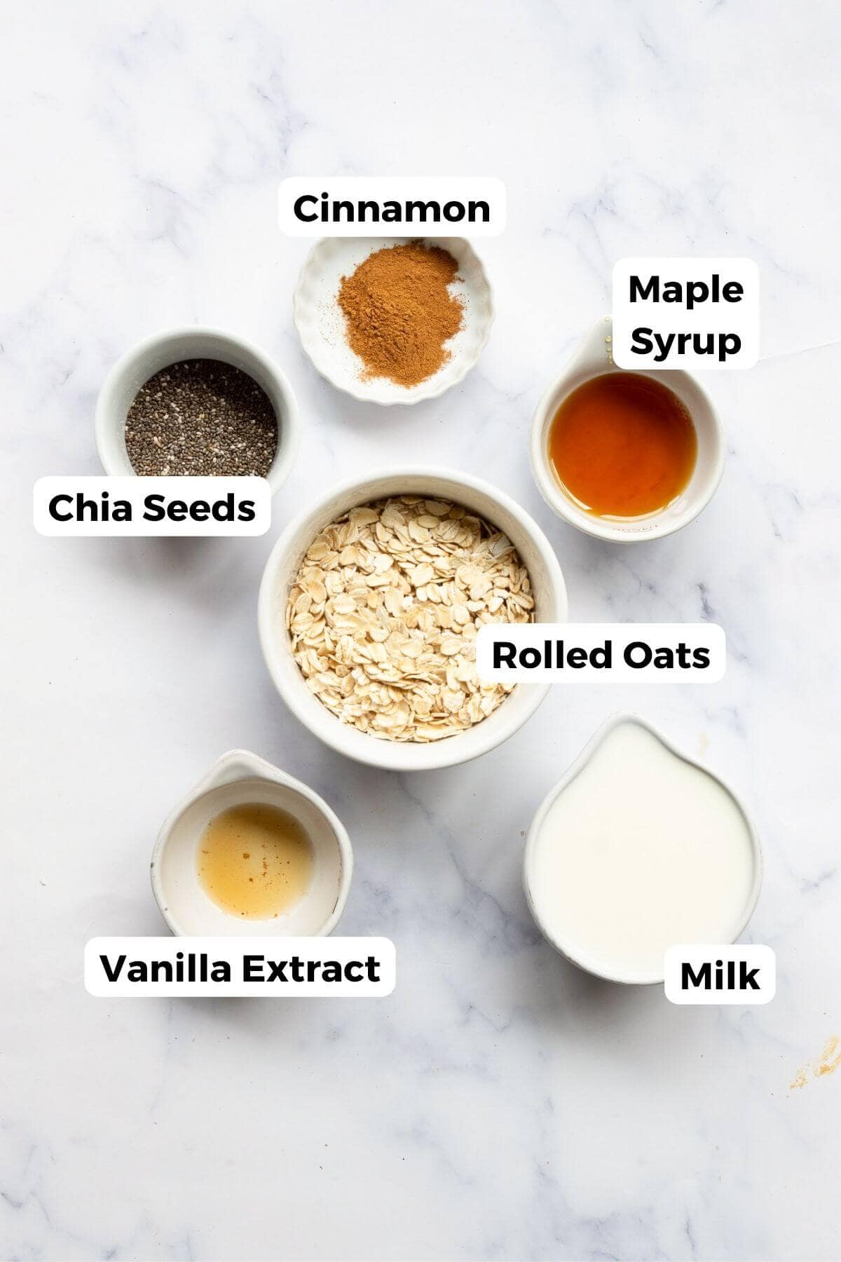 Ingredients for cinnamon overnight oats including rolled oats, chia seeds, cinnamon, maple syrup, and milk.