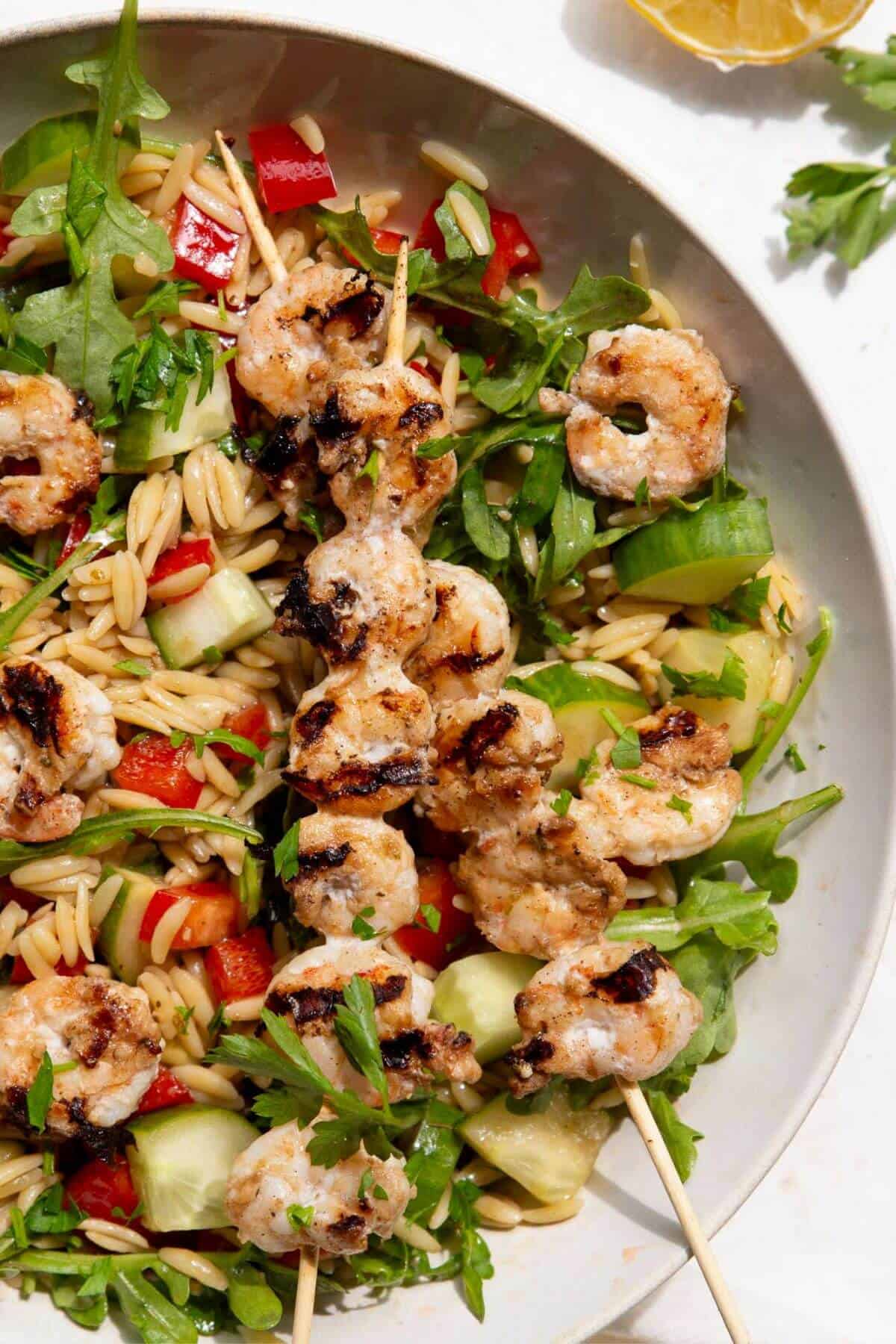 A bowl of high-protein grilled shrimp orzo salad with a balsamic dressing.