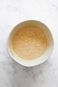 adding egg, milk, maple syrup, and peanut butter to rolled oats