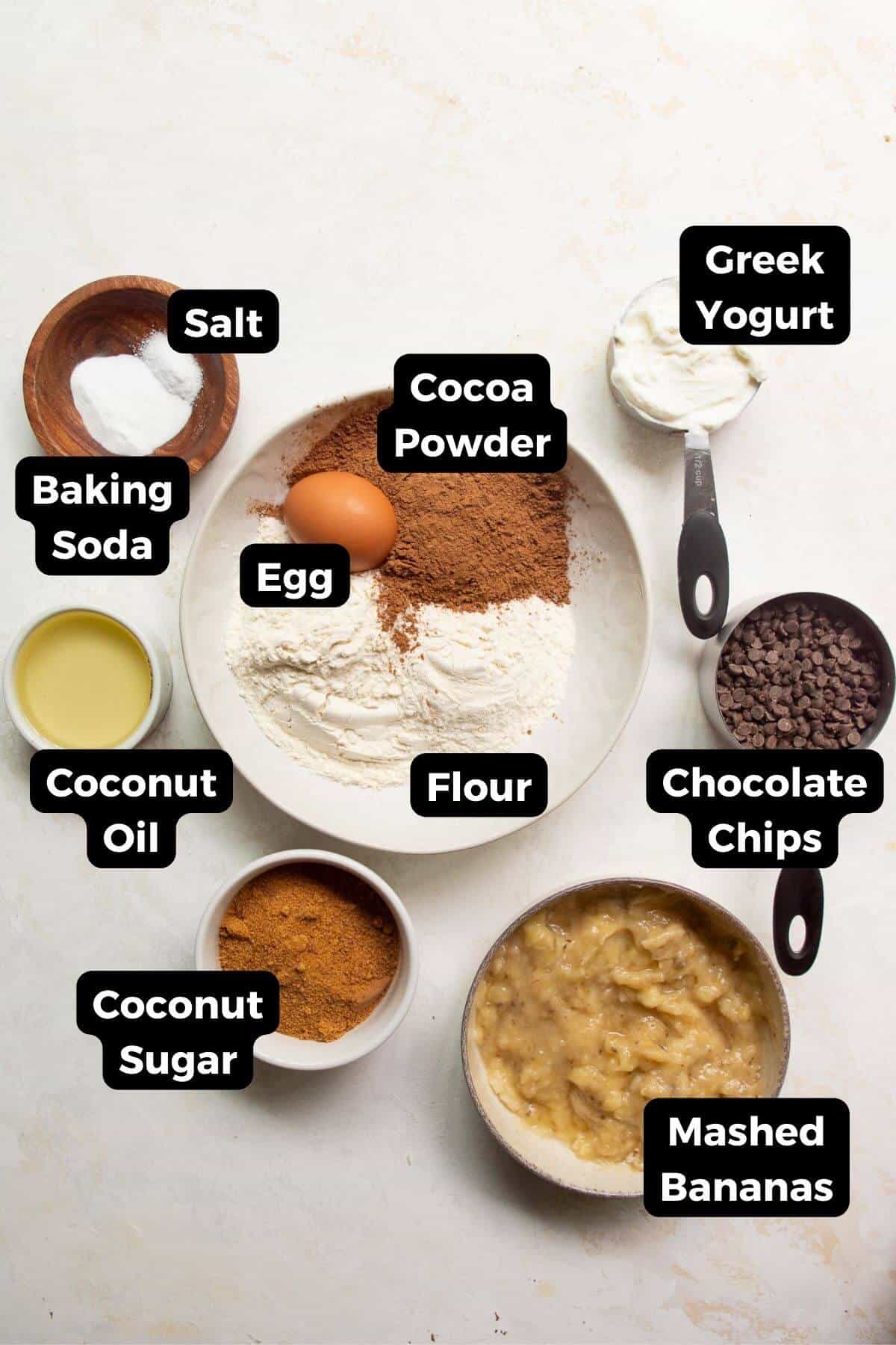 Ingredients for healthy chocolate banana muffins including ripe bananas, cocoa powder, Greek yogurt, coconut sugar, and chocolate chips.